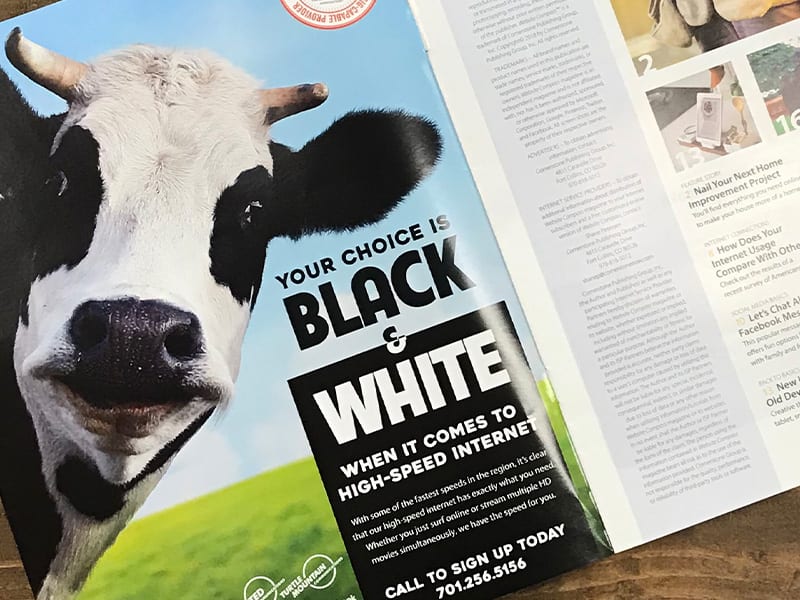 An open magazine displaying a full-page print ad featuring an image of a cow