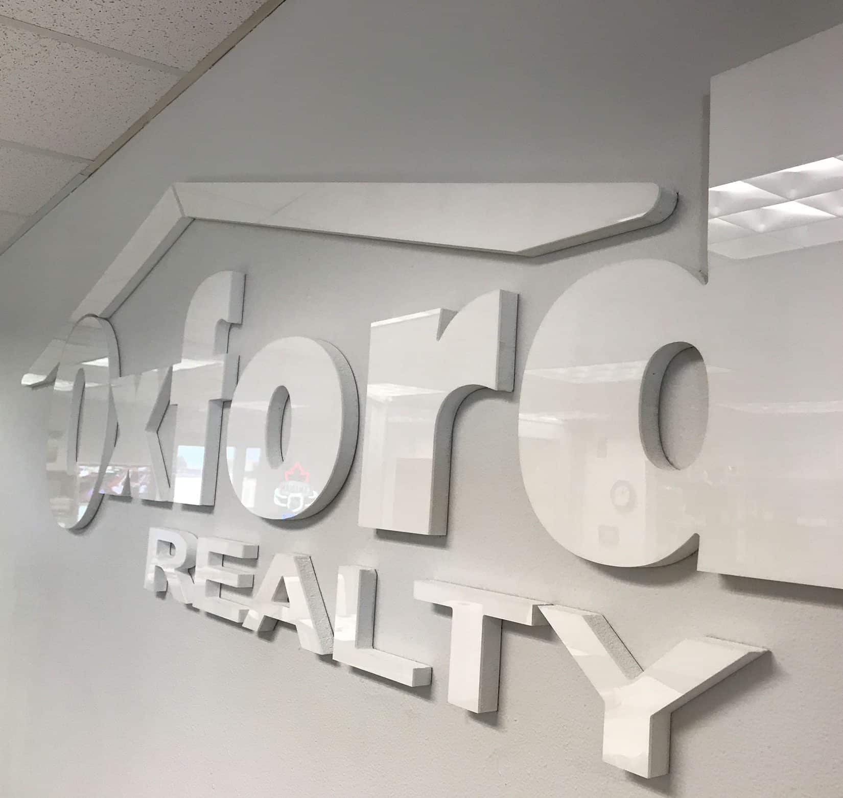 A white sign of Oxford Realty’s logo on a white wall