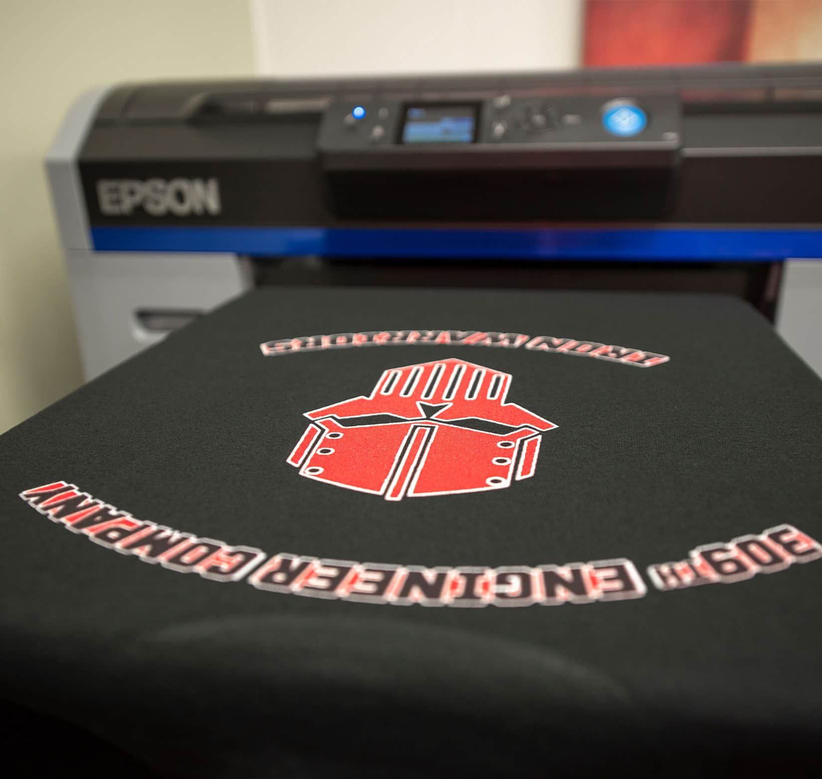 A freshly screen printed black t-shirt coming out of a printer