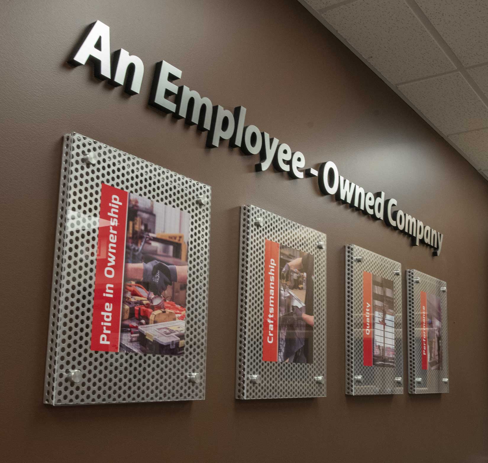 A wall of four framed photos at Custom Aire to recognize company employees