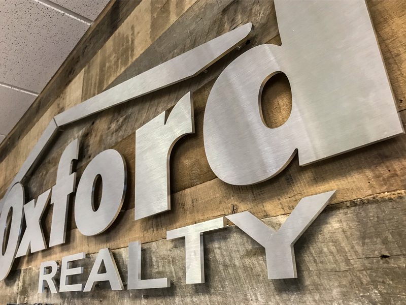 Close up image of a metal sign that says Oxford Realty
