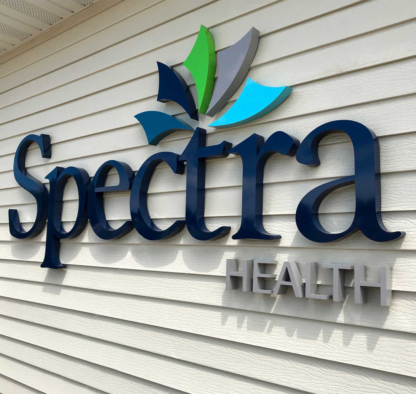 A sign of Spectra Health’s logo installed outside of a building