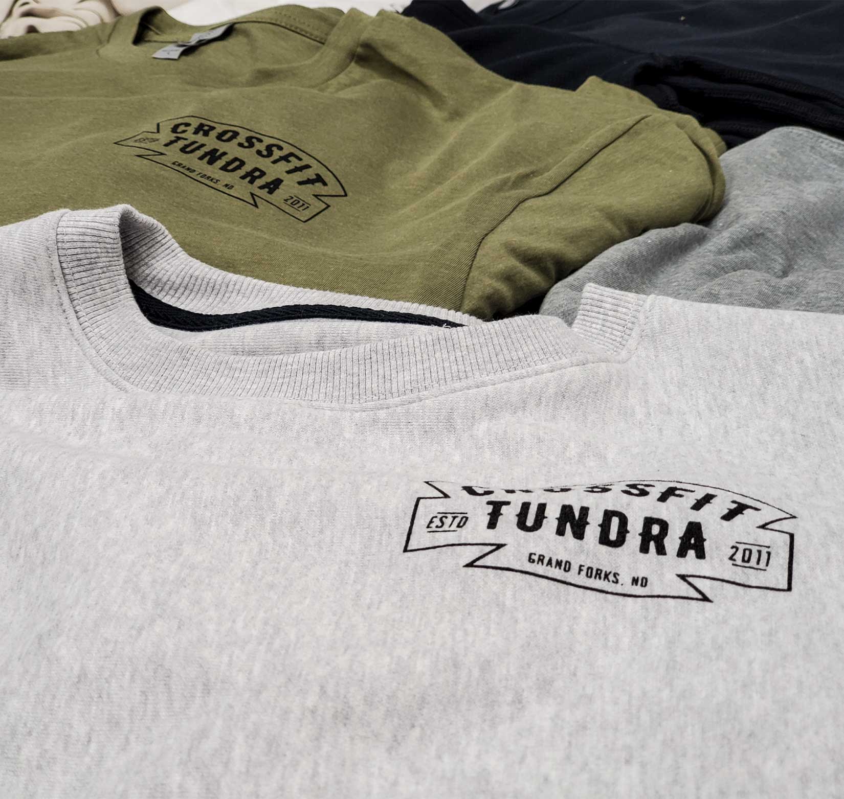 A gray crewneck sweatshirt and a gray t-shirt screen printed with a black CrossFit Tundra logo