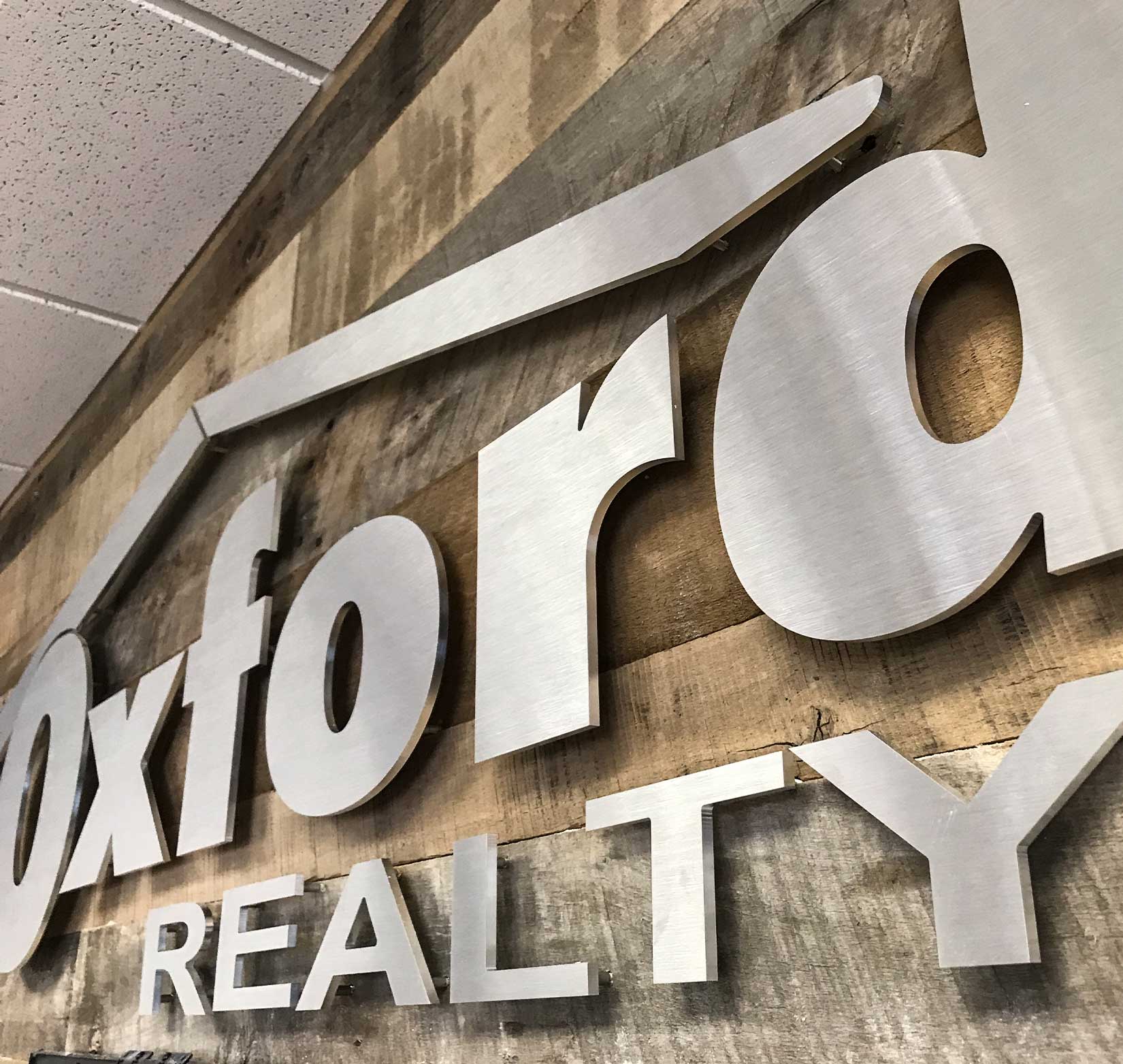 A stainless steel sign of Oxford Realty’s logo