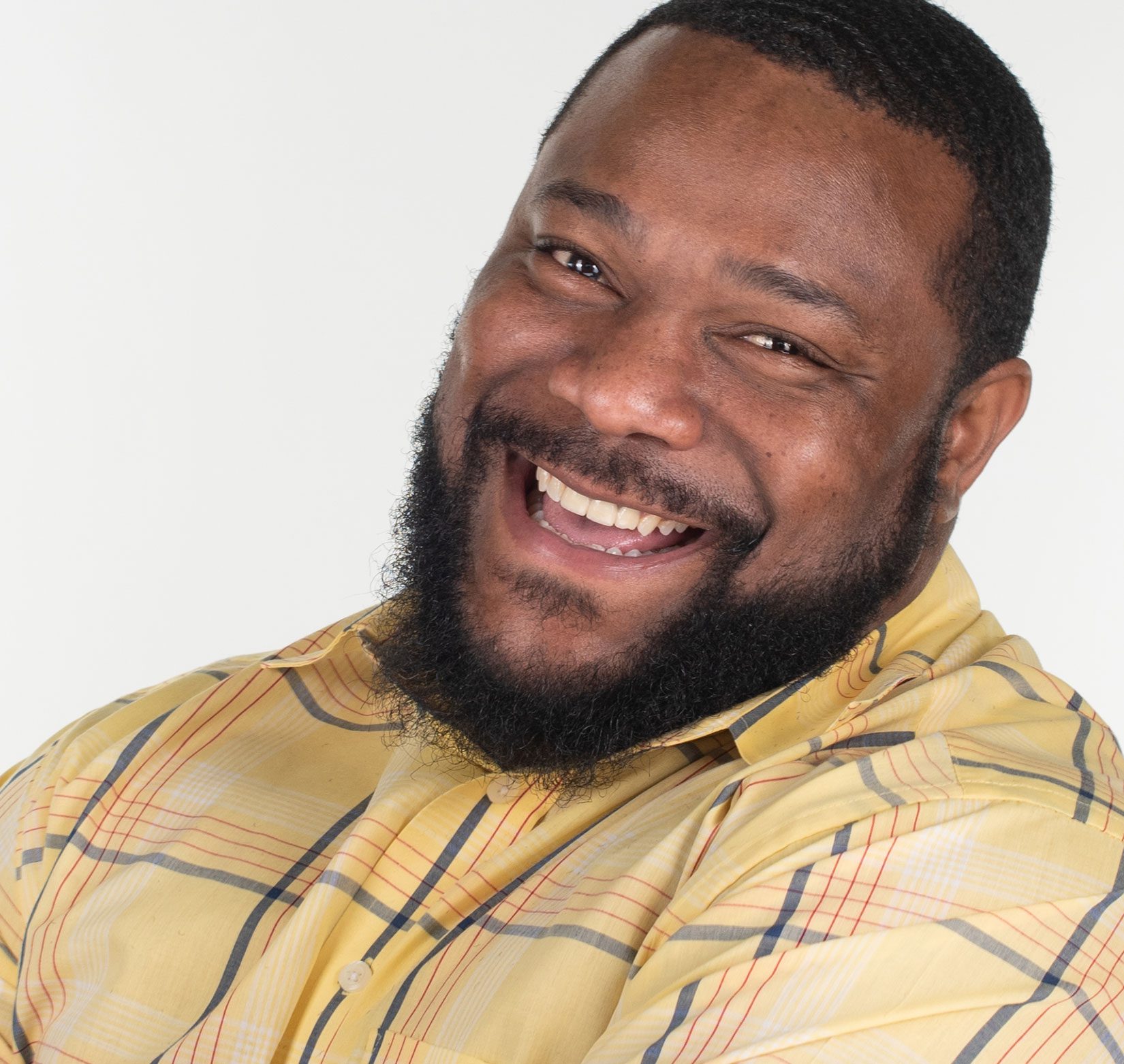 A professional headshot of a middle-aged black male smiling widely