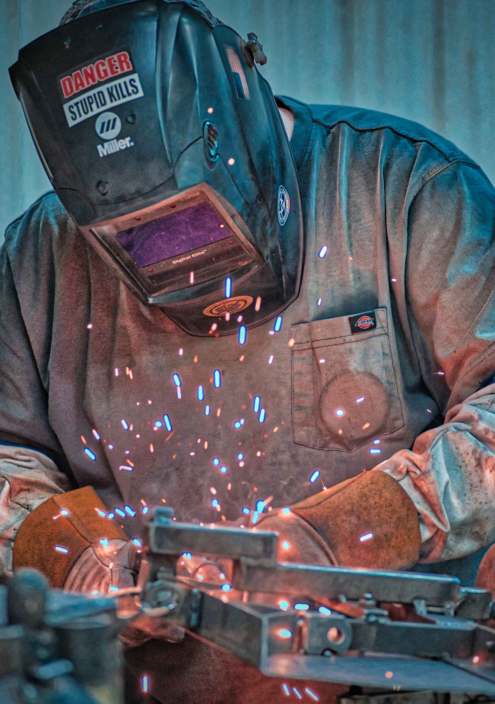 A professional photo of a welder working while wearing a welding mask and gloves