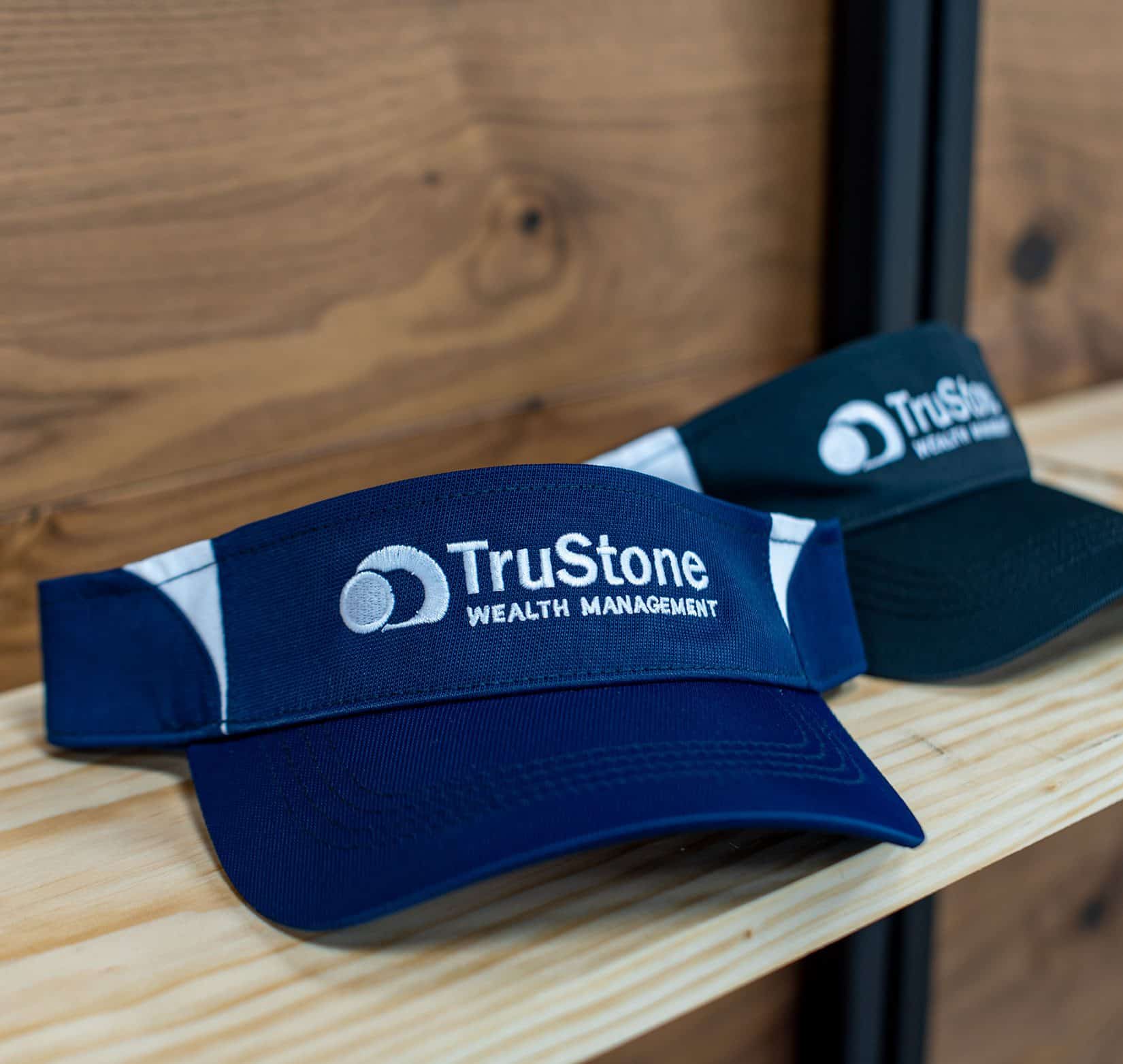 Two visors that have 'TruStone Wealth Management' embroidered on them.